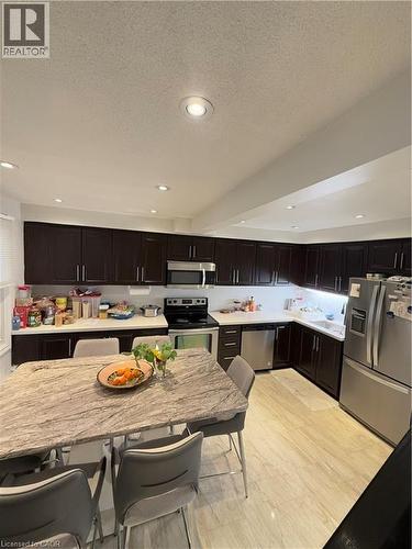 Spacious kitchen featuring dark wood cabinetry, light-toned countertops, and stainless steel appliances - 181 Thaler Avenue, Kitchener, ON 
