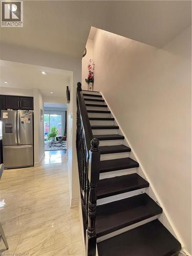 Staircase featuring dark wood-finish treads and balusters with white risers, complemented by recessed ceiling lighting and light-toned tile flooring - 181 Thaler Avenue, Kitchener, ON 