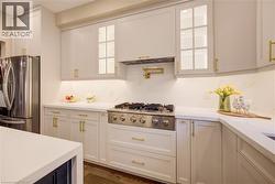 Gourmet kitchen featuring a stainless steel range, white shaker cabinetry with gold-tone hardware, and light-toned countertops - 