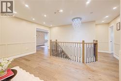 Upper landing featuring wood-finish flooring, recessed lighting, and wainscoting - 