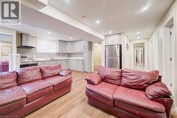 Open-concept living space featuring wood-finish flooring, recessed lighting, and a full kitchen - 