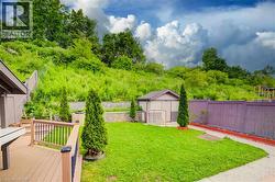Expansive backyard featuring a manicured lawn, a large wooden deck with black metal balusters, a storage shed, and a privacy fence - 