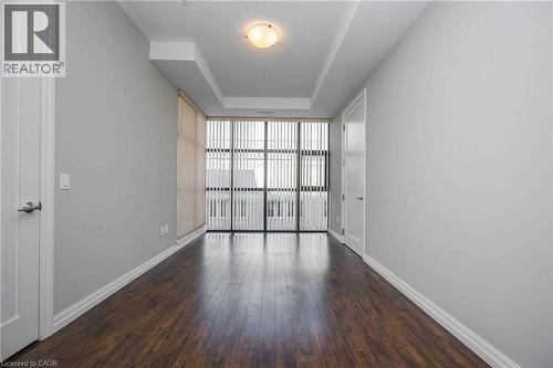 Expansive room featuring dark wood-finish flooring, light gray wall paint, and white baseboards - 112 King Street E Unit# 907, Hamilton, ON 