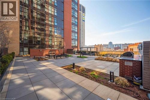 Expansive rooftop patio featuring a paver surface, integrated planter beds, and a built-in brick barbecue station with a countertop - 112 King Street E Unit# 907, Hamilton, ON 