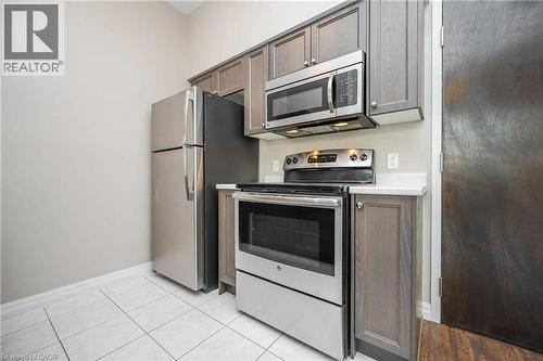 Kitchen featuring stainless steel appliances, grey wood-finish cabinetry, white countertops, and white tile flooring - 112 King Street E Unit# 907, Hamilton, ON 