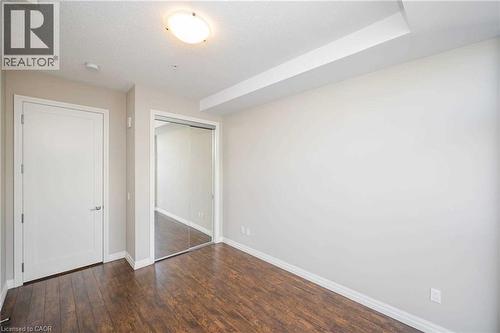 Room featuring wood-finish flooring, a white interior door, and mirrored sliding closet doors - 112 King Street E Unit# 907, Hamilton, ON 
