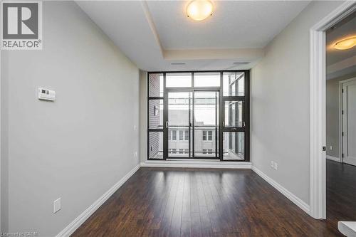 Expansive window wall with sliding glass door, dark wood-finish flooring, light grey painted walls, white baseboards, and a recessed ceiling feature - 112 King Street E Unit# 907, Hamilton, ON 