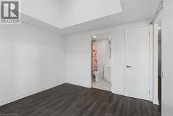 Spacious interior room featuring dark wood-finish flooring, white walls, and high ceilings - 