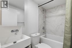 Bathroom featuring a wall-mounted faucet, rectangular sink, white vanity, and a built-in tub with large format tile surround - 