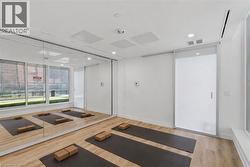 Dedicated fitness space featuring expansive mirrored walls, wood-finish flooring, recessed lighting, and large windows - 