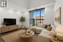Spacious living area featuring high ceilings, recessed lighting, expansive floor-to-ceiling windows, wood-finish flooring, and a neutral color palette - 