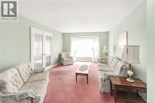 Spacious room featuring a bay window, double French doors, and light green painted walls - 381 Kerman Avenue, Grimsby, ON - Indoor Photo Showing Living Room