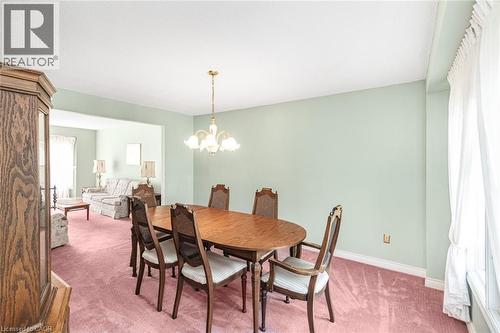 Dining area featuring light green walls, a gold-toned chandelier, and white baseboards - 381 Kerman Avenue, Grimsby, ON - Indoor Photo Showing Dining Room