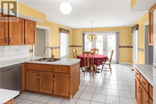 Kitchen featuring light wood cabinetry, white countertops, stainless steel sink with a gooseneck faucet, white tile flooring, and a white tile backsplash - 381 Kerman Avenue, Grimsby, ON - Indoor