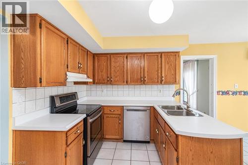 Kitchen featuring wood cabinetry, white countertops, white square tile backsplash, and a double-basin stainless steel sink with a gooseneck faucet - 381 Kerman Avenue, Grimsby, ON - Indoor Photo Showing Kitchen With Double Sink