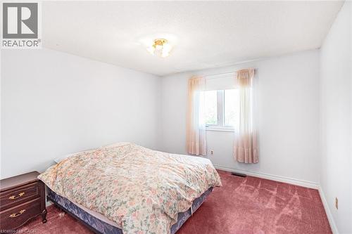 Bright interior space featuring a window, light-colored walls, ceiling-mounted light fixture, and plush red carpeting - 381 Kerman Avenue, Grimsby, ON - Indoor Photo Showing Bedroom