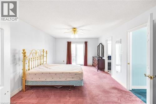 Spacious room featuring broadloom carpeting, light wall tones, a ceiling fan fixture, and a sliding door providing exterior access - 381 Kerman Avenue, Grimsby, ON - Indoor Photo Showing Bedroom