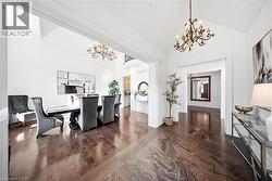 Spacious entryway featuring a large dining area with vaulted ceilings, crystal chandeliers, wood-finish flooring, and a stone tile inlay - 