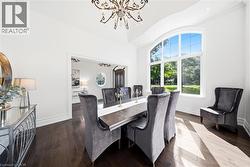 Dining room featuring hardwood flooring, an arched picture window, a decorative chandelier, and crown molding - 