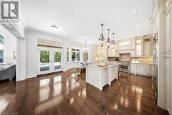 Gourmet kitchen with wood-finish flooring, white cabinetry, a central island with a light-toned countertop, and stainless steel appliances - 