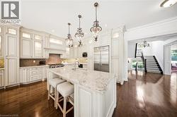 Kitchen featuring a large central island with seating, white cabinetry with glass-front accents, and stainless steel appliances - 