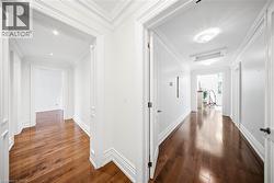 Hallway featuring wood-finish flooring, white walls, and extensive crown molding - 