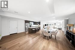 Open-concept living area featuring wood-finish flooring, recessed lighting, and white baseboards - 