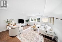 Spacious living area featuring wood-finish flooring, recessed lighting, and a floating entertainment console - 