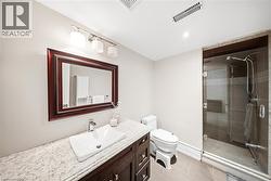 Contemporary bathroom featuring a dark wood-finish vanity with a vessel sink, a granite-style countertop, a framed mirror, a glass-enclosed shower, and neutral tile flooring - 