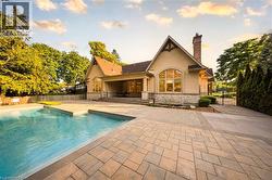 Exterior of a stucco and stone-clad residence featuring a gable roofline and prominent arched window - 