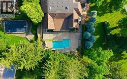 Expansive property featuring two distinct swimming pools, one with a diving board, surrounded by lush green lawns and mature trees - 