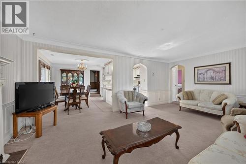 Spacious living area featuring carpet flooring, decorative wainscoting, and an open archway leading to the dining space - 114 E Second Road E, Stoney Creek, ON 