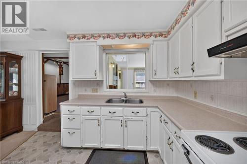 Kitchen featuring white cabinetry, a double basin stainless steel sink, and a four-burner electric range with an overhead vent - 114 E Second Road E, Stoney Creek, ON 