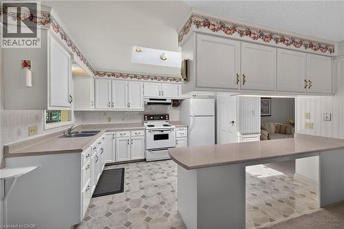 Kitchen featuring white cabinetry, light-toned countertops, integrated sink, and an electric range - 114 E Second Road E, Stoney Creek, ON 
