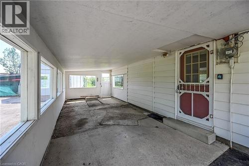 Enclosed porch featuring multiple windows, a ceiling fan, concrete flooring, and a red screen door - 114 E Second Road E, Stoney Creek, ON 