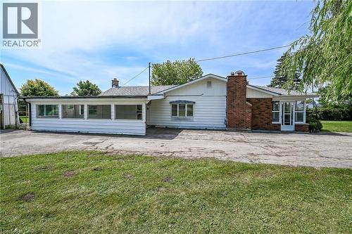 White siding exterior with a prominent brick chimney and a large paved area - 114 E Second Road E, Stoney Creek, ON 