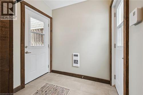 Entryway featuring two white panel doors with glass inserts, robust wood-finish trim, and light-toned tile flooring - 838 Moore Street, Cambridge, ON - Indoor Photo Showing Other Room
