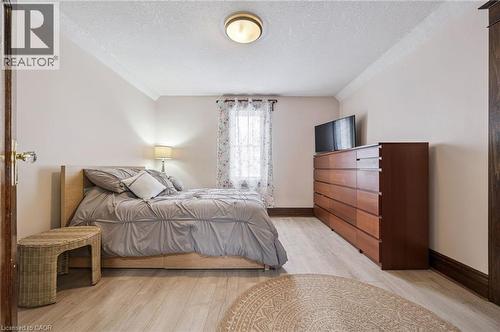 Bedroom featuring wood-finish flooring, a window with sheer curtains, crown molding, and a flush-mount ceiling light fixture - 838 Moore Street, Cambridge, ON - Indoor Photo Showing Bedroom