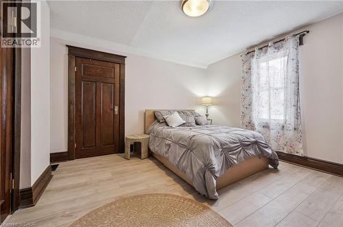 Light wood-finish flooring complements white walls and dark wood trim - 838 Moore Street, Cambridge, ON - Indoor Photo Showing Bedroom