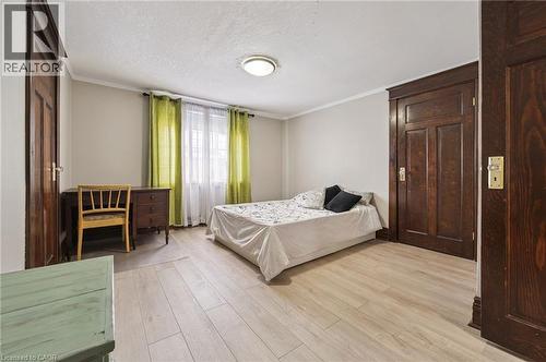 Light wood-finish flooring complements the neutral wall color - 838 Moore Street, Cambridge, ON - Indoor Photo Showing Bedroom