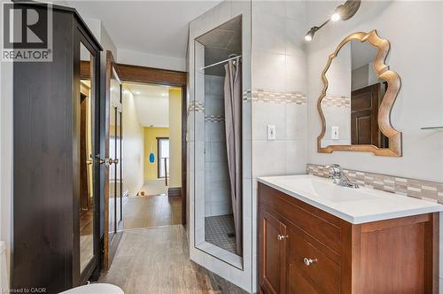 Bathroom featuring a wood vanity with integrated sink, a decorative mirror, tiled shower enclosure, wood-finish flooring, and track lighting - 838 Moore Street, Cambridge, ON - Indoor Photo Showing Bathroom