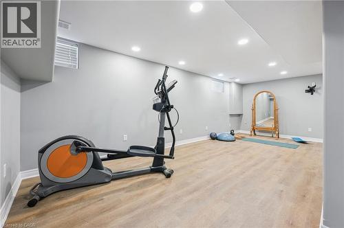 Finished basement recreation room with wood-finish flooring, recessed lighting, light gray walls, and white trim - 838 Moore Street, Cambridge, ON - Indoor Photo Showing Gym Room
