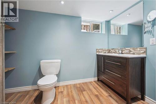 Bathroom featuring a wood-finish vanity with an integrated sink and a mosaic tile backsplash - 838 Moore Street, Cambridge, ON - Indoor Photo Showing Bathroom