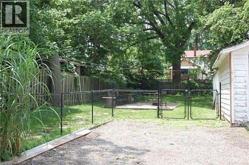 Expansive gravel driveway leading to a gated, fenced yard with mature trees - 838 Moore Street, Cambridge, ON - Outdoor