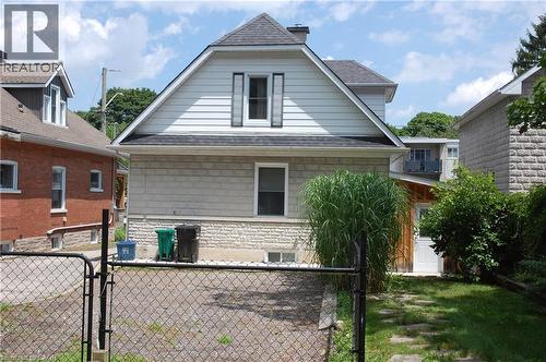 Rear elevation featuring a white siding upper level with dark shutters, and a stone-finish lower level - 838 Moore Street, Cambridge, ON - Outdoor With Exterior