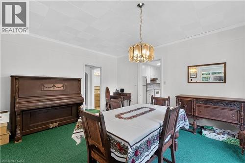 Dining area featuring a decorative ceiling light fixture, crown molding, and a pass-through opening to the kitchen - 1629 Gregory Road, St. Catharines, ON 