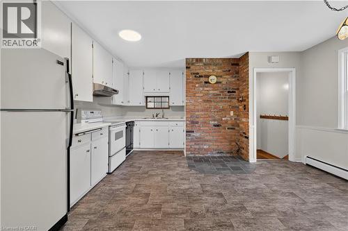 Kitchen featuring extensive white cabinetry, white appliances, and vinyl flooring - 1629 Gregory Road, St. Catharines, ON 