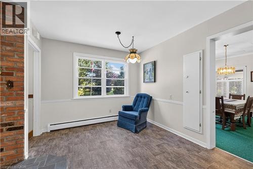 Interior space featuring wood-vinyl flooring, a large window, and light-toned walls with wainscoting - 1629 Gregory Road, St. Catharines, ON 