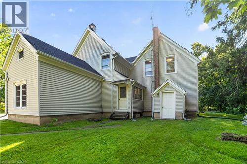 Rear facade of a residential structure featuring light-colored horizontal siding, a dark shingle roof, and multiple gabled sections - 1629 Gregory Road, St. Catharines, ON 