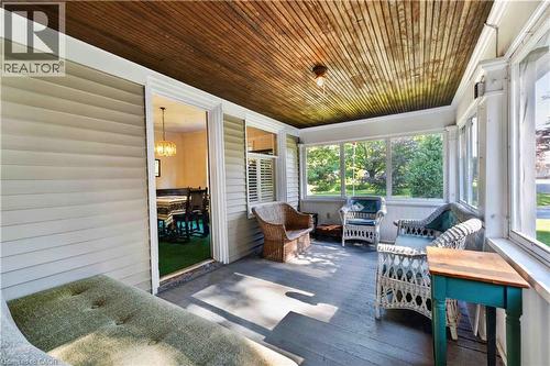 Enclosed porch featuring a wood-paneled ceiling, painted wood flooring, and multiple large windows - 1629 Gregory Road, St. Catharines, ON 